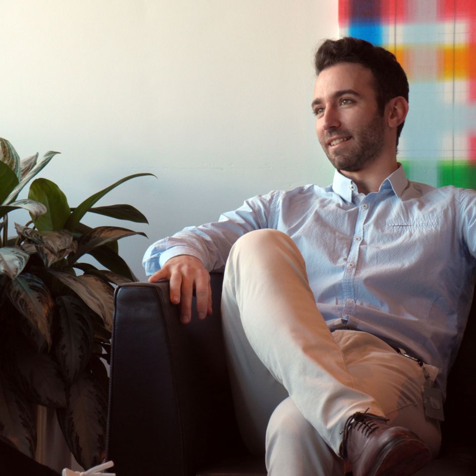 A male sitting on an armchair and smiling.