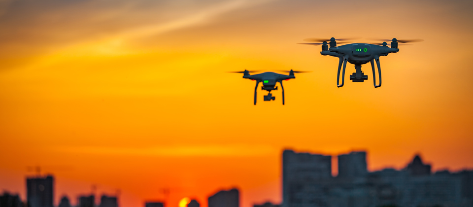 Drones in the air with a skyline in the background.