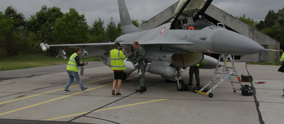 Pilot, videomakers, and photographer working around an F-16 on the ground.