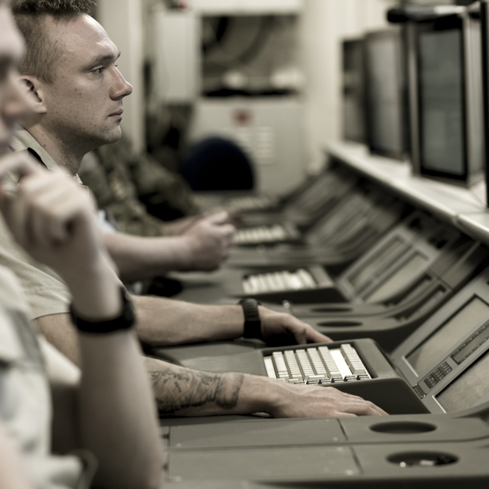 Military employees looking at monitors in the command and control room.