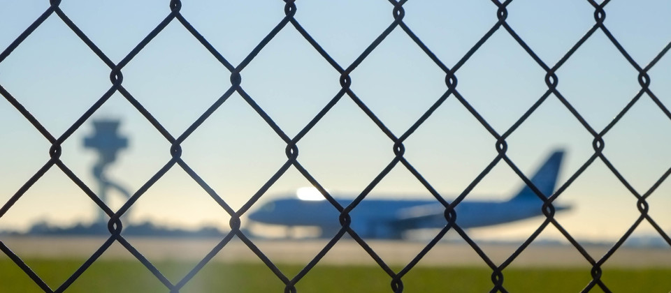 Aircraft behind a fence at the airport.