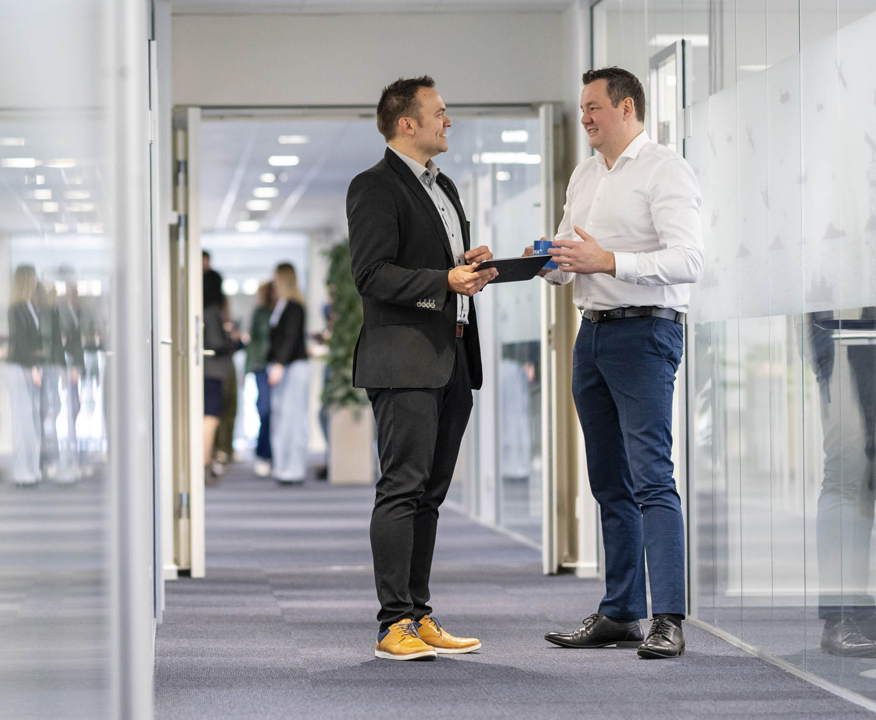 Two men in suits shake hands in a large office. AI generated content
