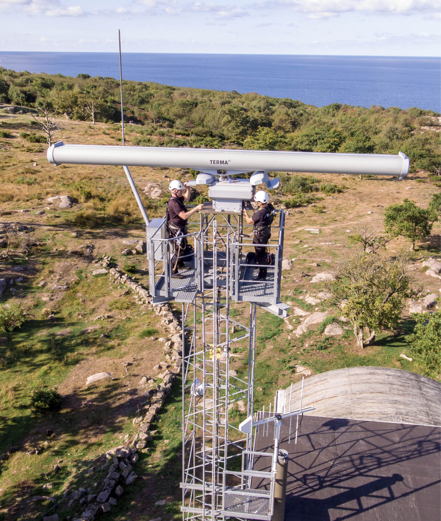 Two men are on a platform overlooking a field. Description generated by AI
