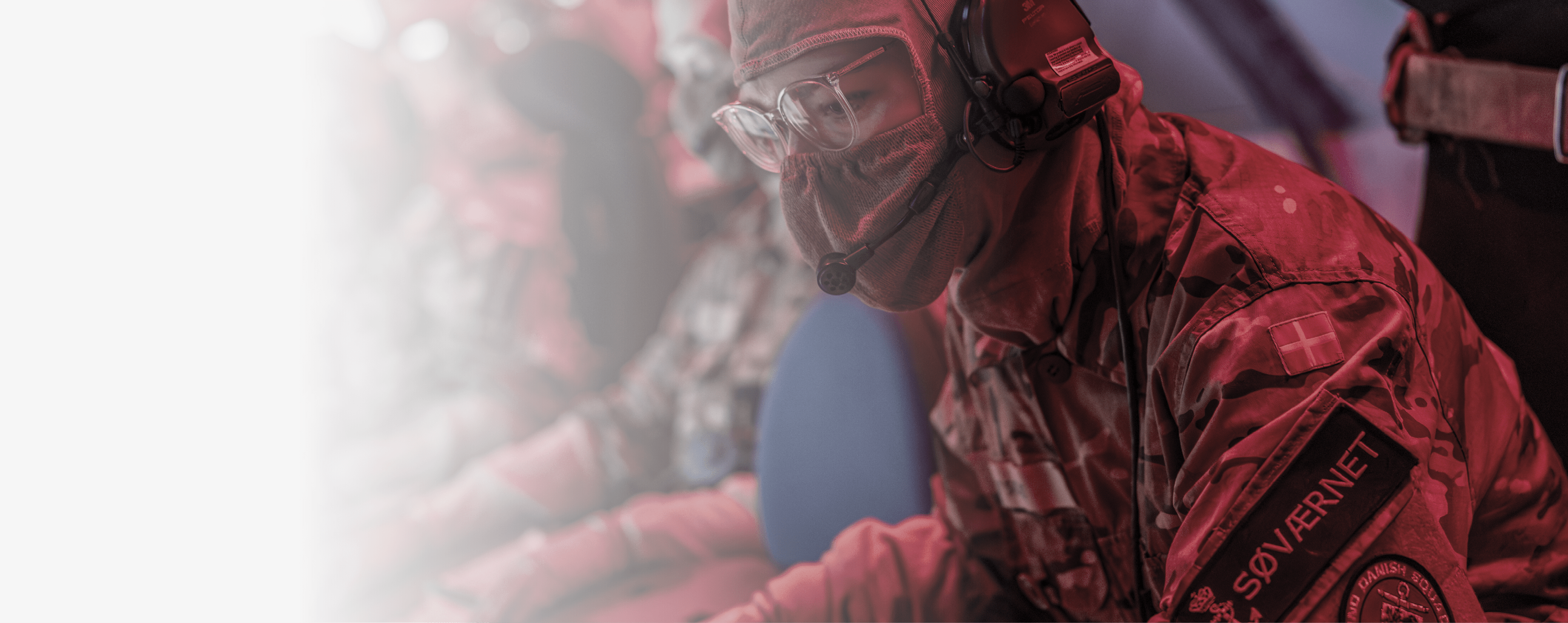 A man wearing a gas mask and camouflage is sitting in front of a computer. AI generated content